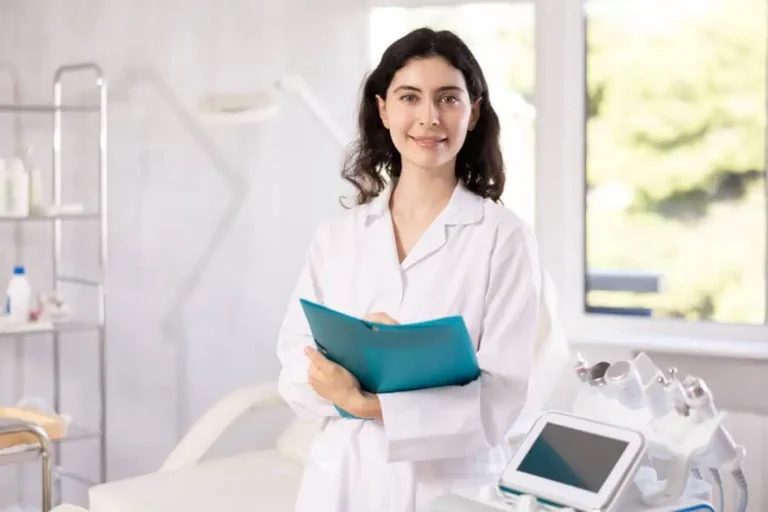 A cosmetic dermatology practitioner holding a client chart beside her treatment equipment
