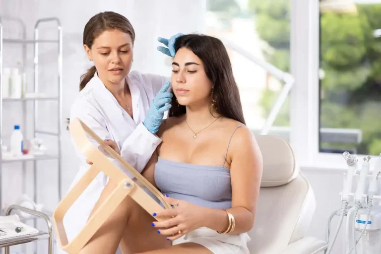 A practitioner holding a mirror while treating a seated med spa client